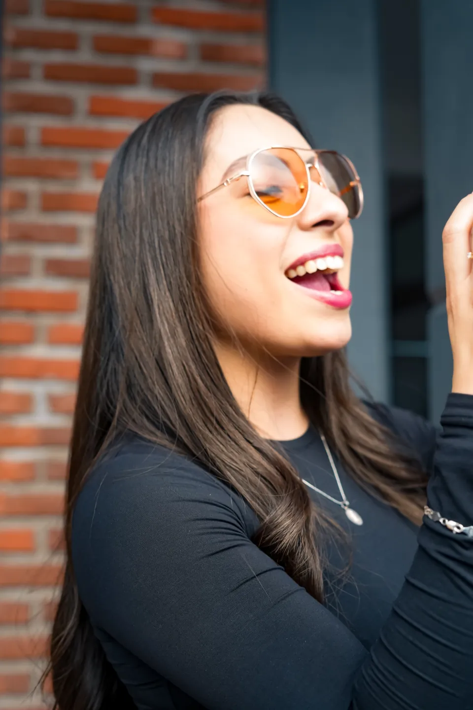 Risa con lentes frente al ladrillo