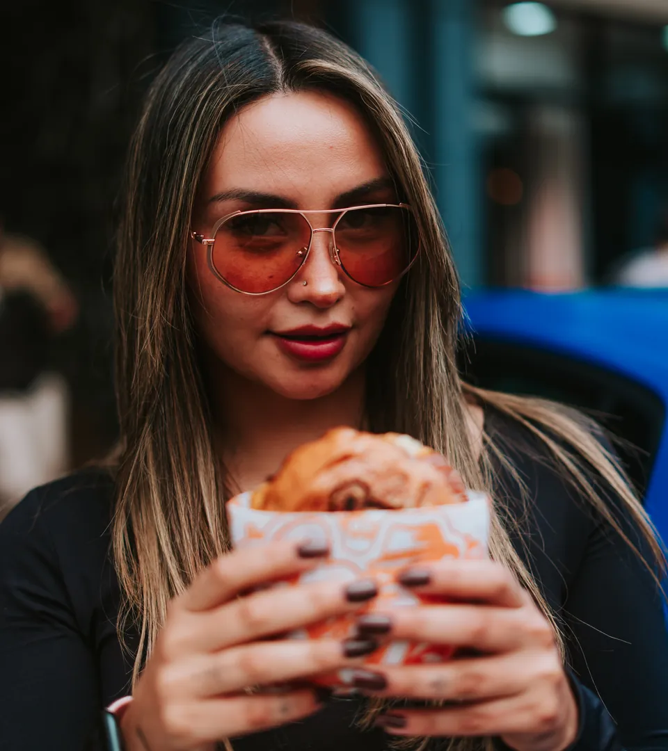 Chica con lentes y su burger junto al coche